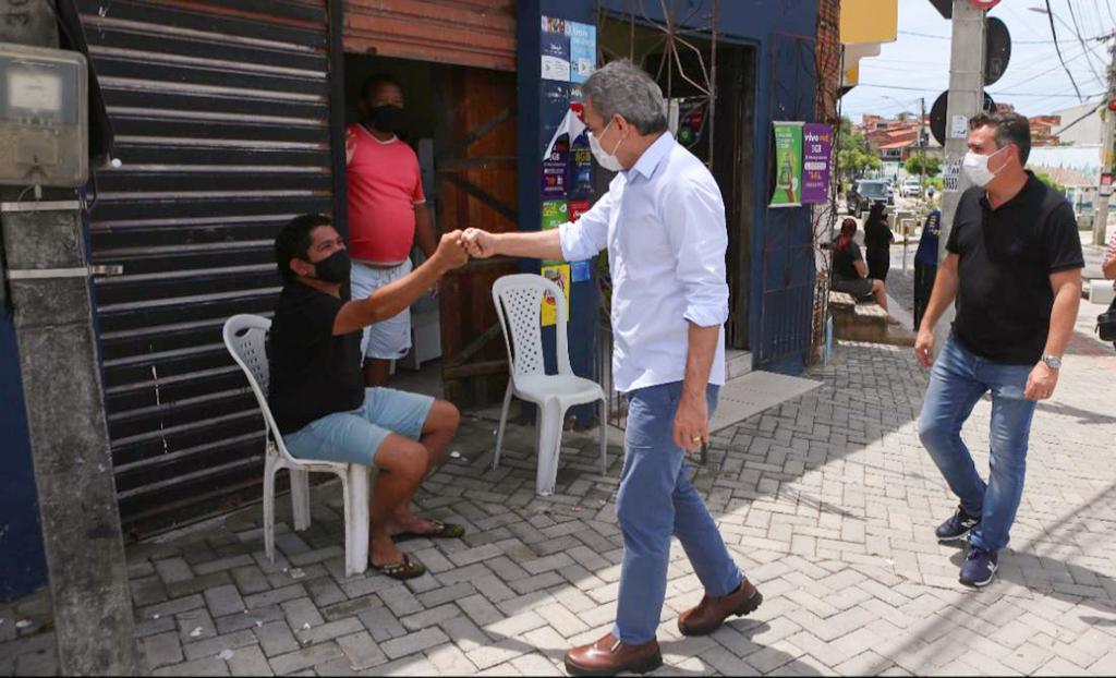 Sarto cumprimenta um senhor sentado em uma cadeira na calçada de uma rua no vicente pinzpon